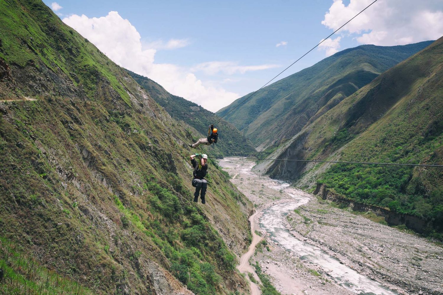 Tourists riding a long zipline high across a deep river valley canyon in Santa Teresa Cusco