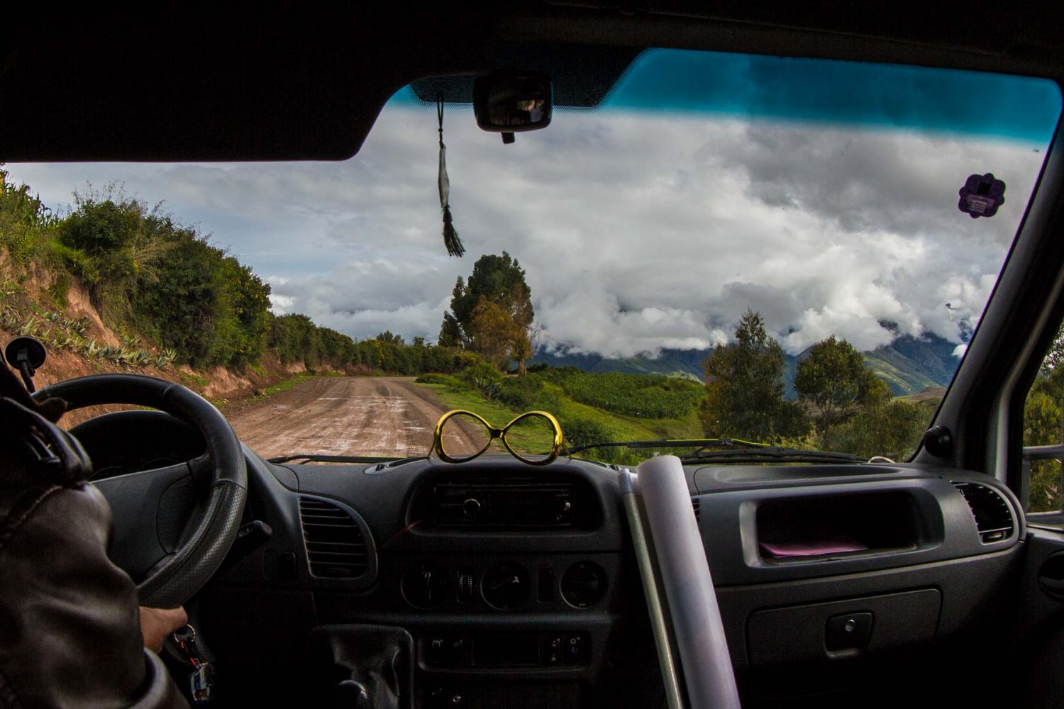 Mountain bikers riding downhill along a winding road surrounded by massive Andean peaks in Cusco