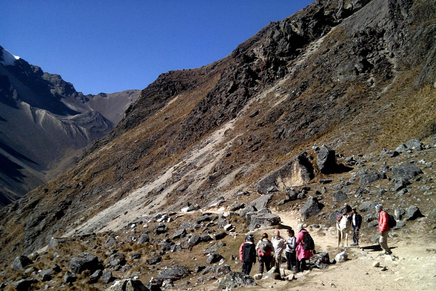Towering sharp snow-covered glacier peak of Mount Salkantay against bright blue sky