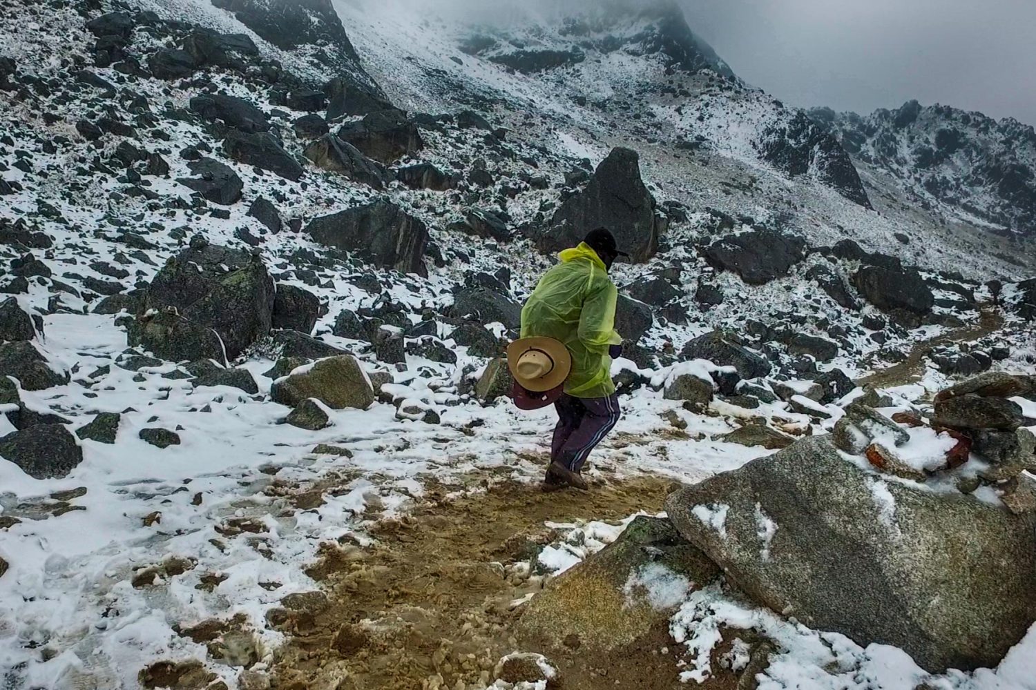 Hikers ascending the rocky terrain of the Salkantay Pass surrounded by grey mountain ridges