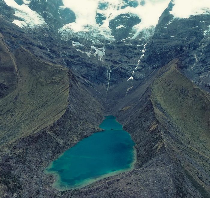 Turquoise waters of Humantay Lake surrounded by dramatic snow glacier peaks on the Salkantay Trek