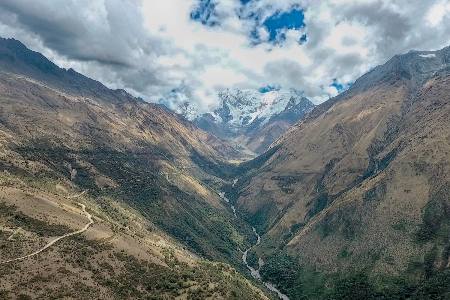 Active travelers hiking along a rocky path with a green mountain valley in the distance Salkantay Trek