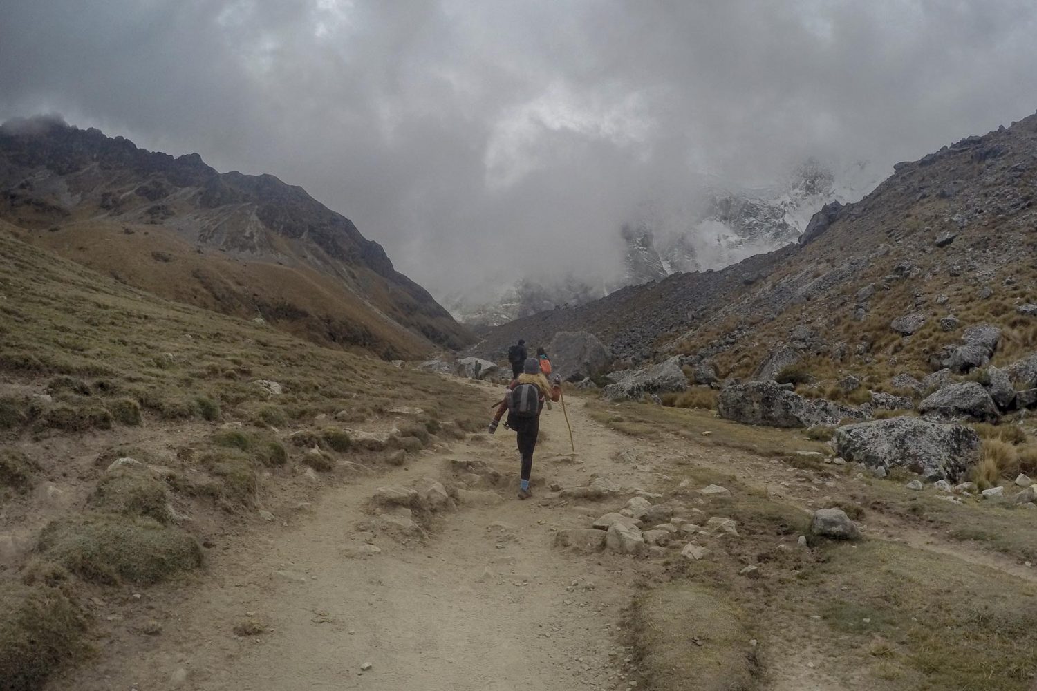 Hikers trekking on the alpine trail heading directly towards the massive Salkantay peak in Cusco
