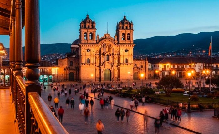 Vista nocturna de la Plaza de Armas iluminada, reflejando la animada vida nocturna en Cusco con gente paseando y luces cálidas de los balcones.