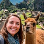 Turista europea tomando una selfie con una alpaca en Machu Picchu, Perú.