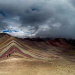 A breathtaking view of Vinicunca, Peru’s iconic Rainbow Mountain near Cusco, featuring vibrant natural stripes of red, yellow, and turquoise under a clear Andean sky.