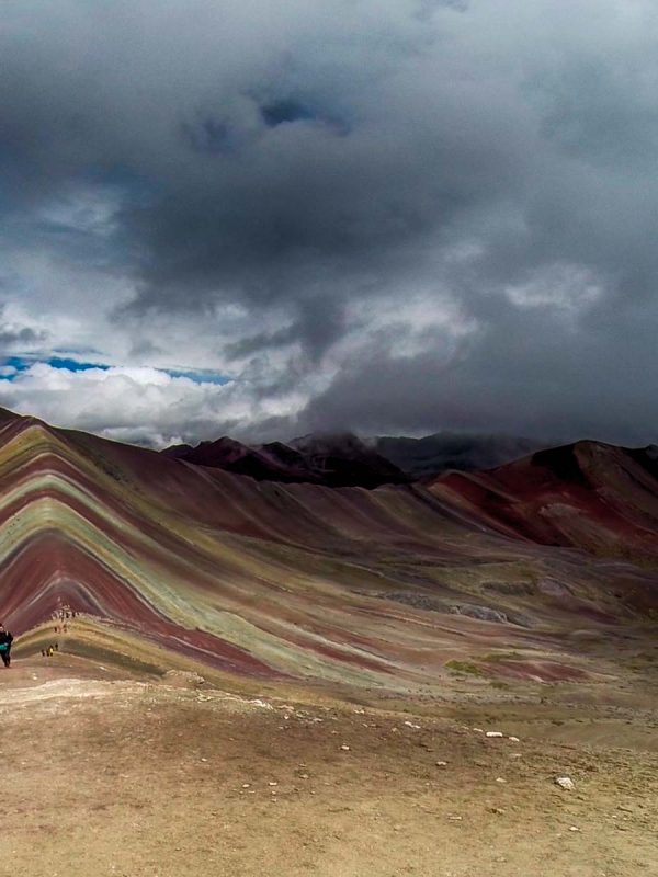 A breathtaking view of Vinicunca, Peru’s iconic Rainbow Mountain near Cusco, featuring vibrant natural stripes of red, yellow, and turquoise under a clear Andean sky.