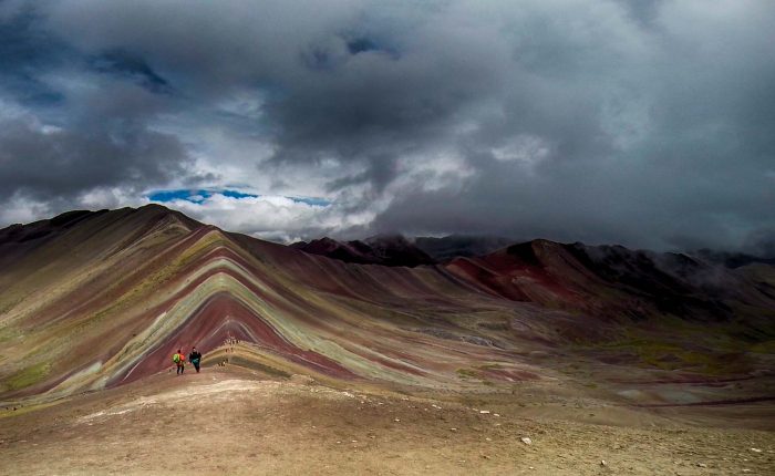 A breathtaking view of Vinicunca, Peru’s iconic Rainbow Mountain near Cusco, featuring vibrant natural stripes of red, yellow, and turquoise under a clear Andean sky.