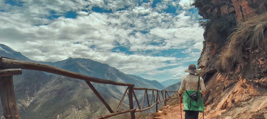 Un caminante observando el sendero en zigzag que muestra cómo llegar a Choquequirao, con el imponente cañón del río Apurímac de fondo.