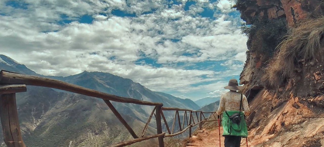 Un caminante observando el sendero en zigzag que muestra cómo llegar a Choquequirao, con el imponente cañón del río Apurímac de fondo.