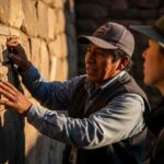 Un buen guía de turismo explicando con pasión la historia de unas ruinas incas a un grupo de viajeros atentos en los Andes de Perú