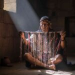 Un sabio Quipucamayoc en una cámara de piedra iluminada por un rayo de sol, examinando el código secreto de los quipus, la escritura perdida del Imperio Inca.