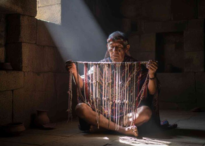 Un sabio Quipucamayoc en una cámara de piedra iluminada por un rayo de sol, examinando el código secreto de los quipus, la escritura perdida del Imperio Inca.