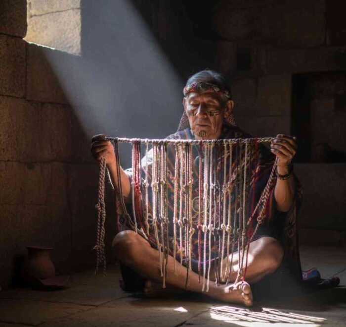 Un sabio Quipucamayoc en una cámara de piedra iluminada por un rayo de sol, examinando el código secreto de los quipus, la escritura perdida del Imperio Inca.