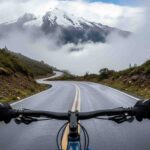 Un ciclista en pleno descenso en bicicleta Inka Jungle, visto desde su perspectiva (POV), bajando la neblinosa carretera del Abra Málaga hacia la selva