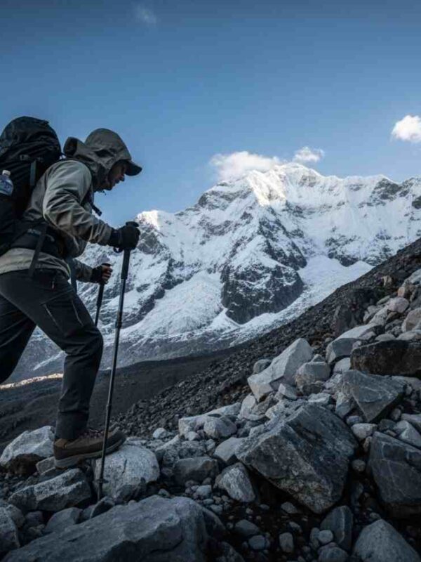 Un viajero en medio del ascenso del día 2 en Salkantay, con el imponente pico nevado del Apu Salkantay de fondo