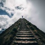Un excursionista llegando a la cima del paso más alto, ilustrando la verdadera dificultad del Camino Inca frente a la inmensidad de los Andes