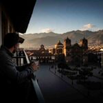 Un viajero pensativo mirando la Plaza de Armas de Cusco al amanecer, experimentando el vacío post-Machu Picchu