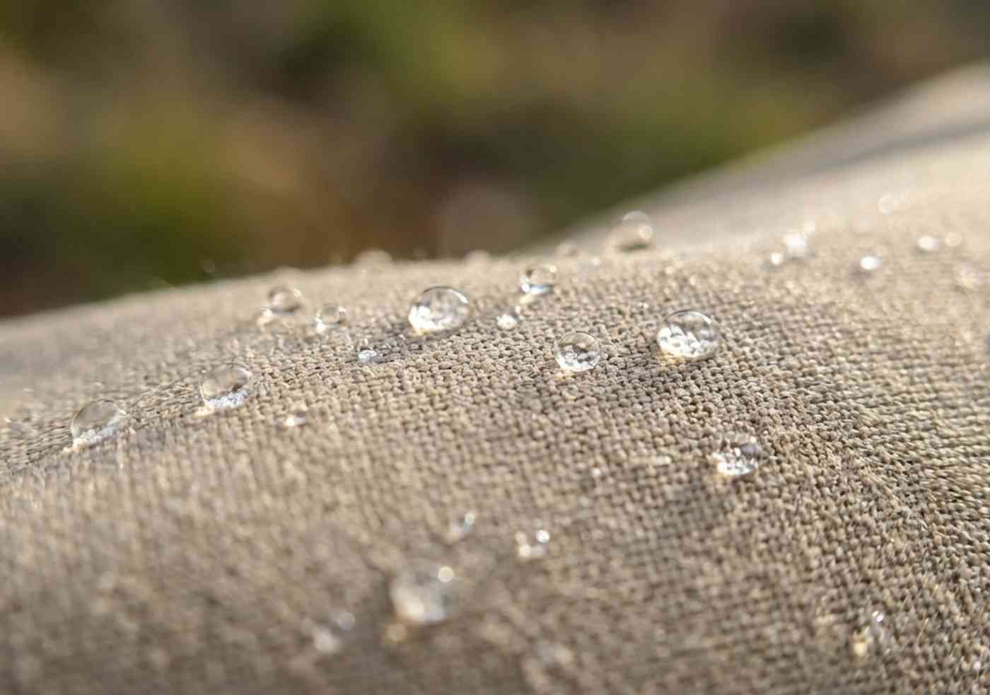 Primer plano de gotas de agua resbalando sobre una tela técnica de poliéster de color beige