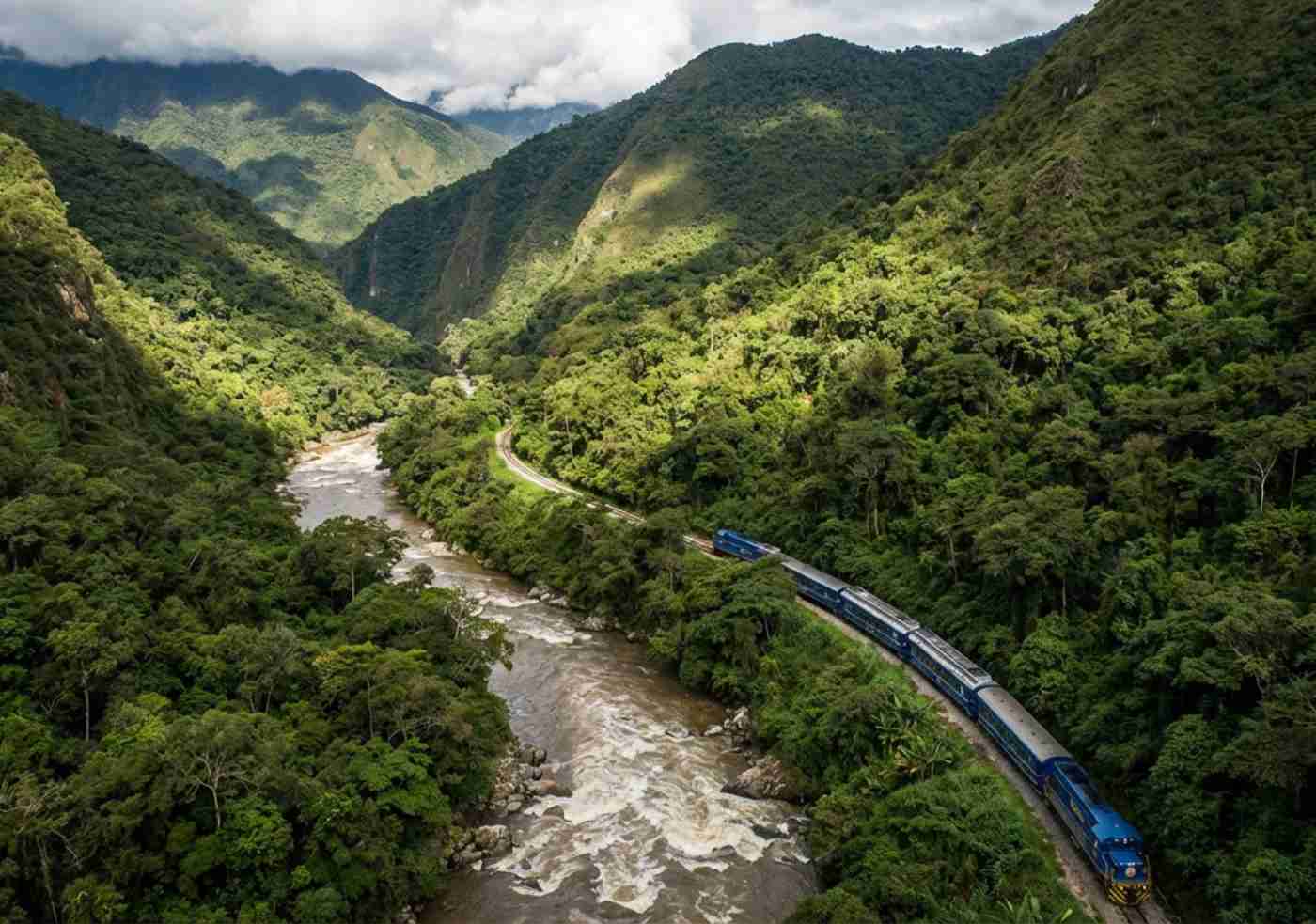 Vista aérea del tren azul cruzando el río Urubamba rodeado de vegetación densa