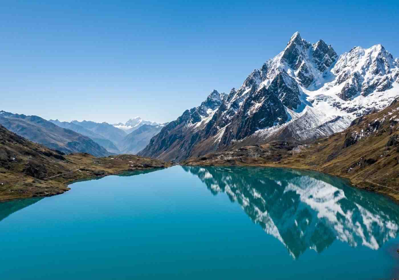 Laguna turquesa al pie del Nevado Ausangate con visibilidad perfecta del glaciar reflejado en el agua.