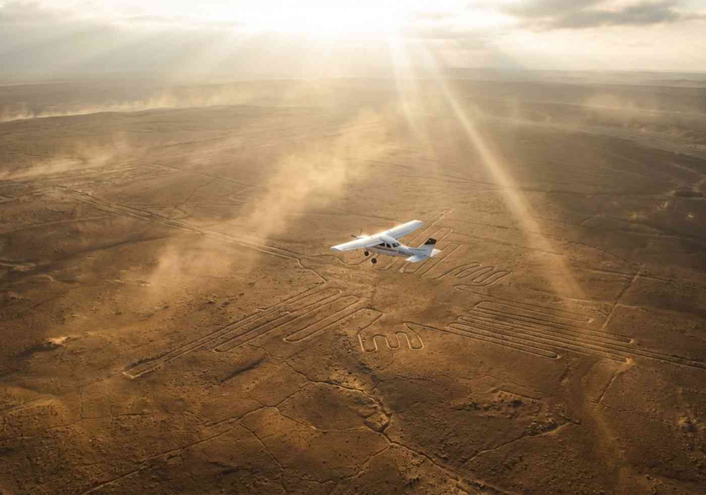 Vista aérea épica de una avioneta Cessna sobrevolando el geoglifo del Colibrí en el desierto de Nazca bajo una luz dorada.