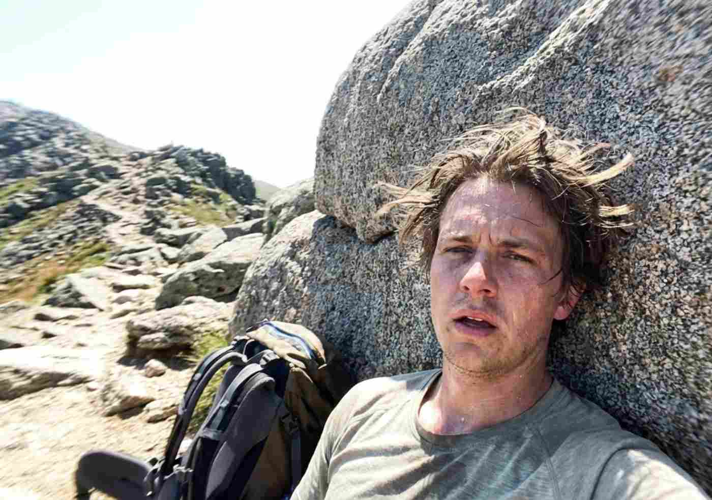 Viajero descansando con cansancio visible en el sendero empinado hacia Laguna 69 en Huaraz