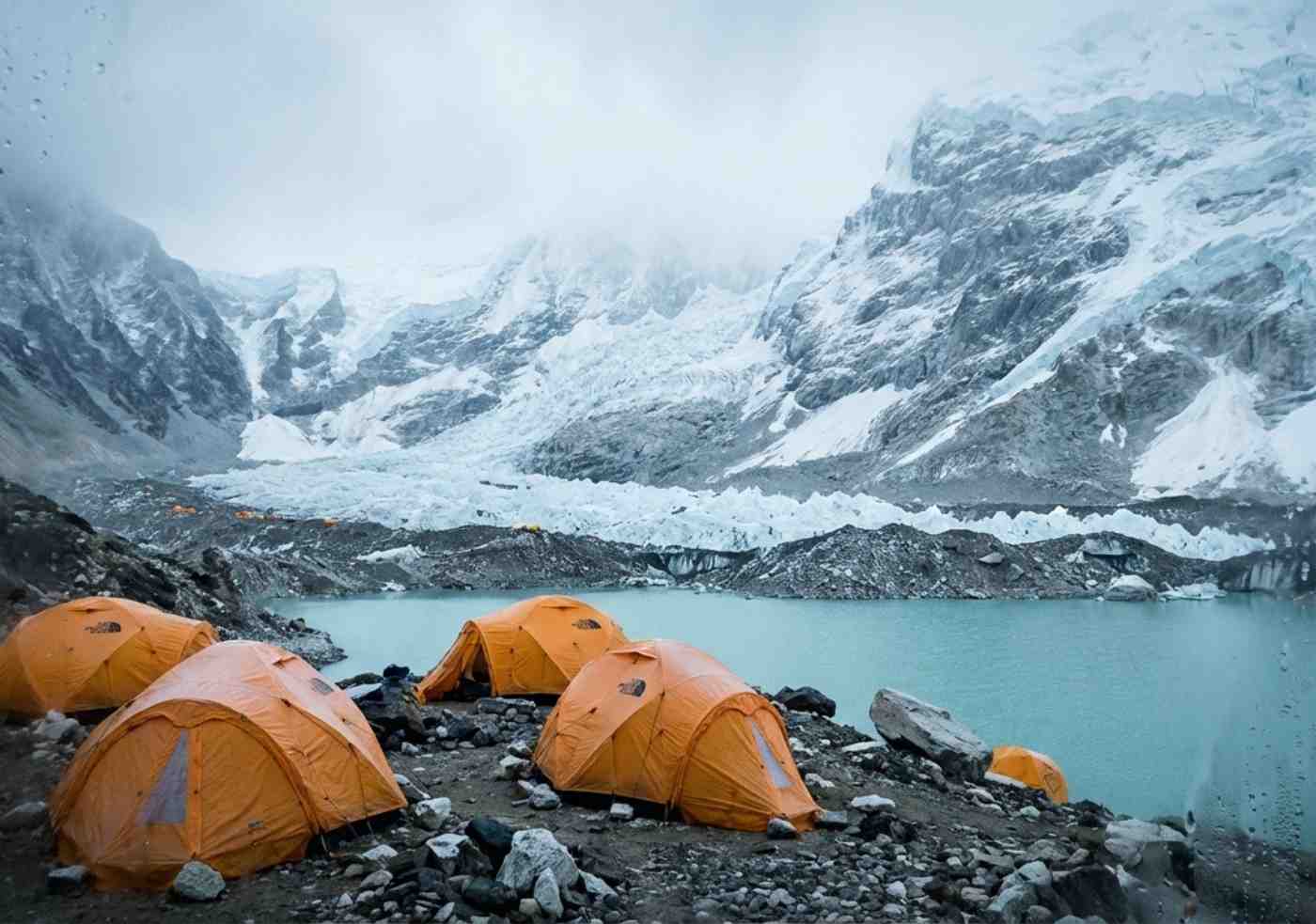 Carpas de alta montaña instaladas frente a una laguna glacial bajo la niebla matutina en el Ausangate Trek.
