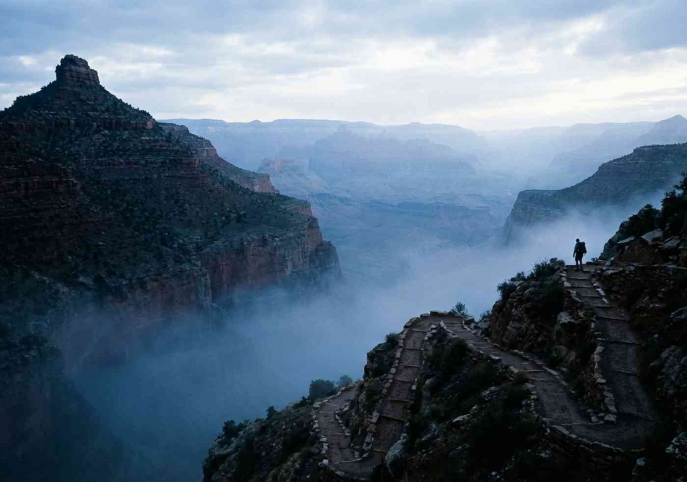 Excursionista ascendiendo los zigzags del Colca bajo una luz suave de madrugada.