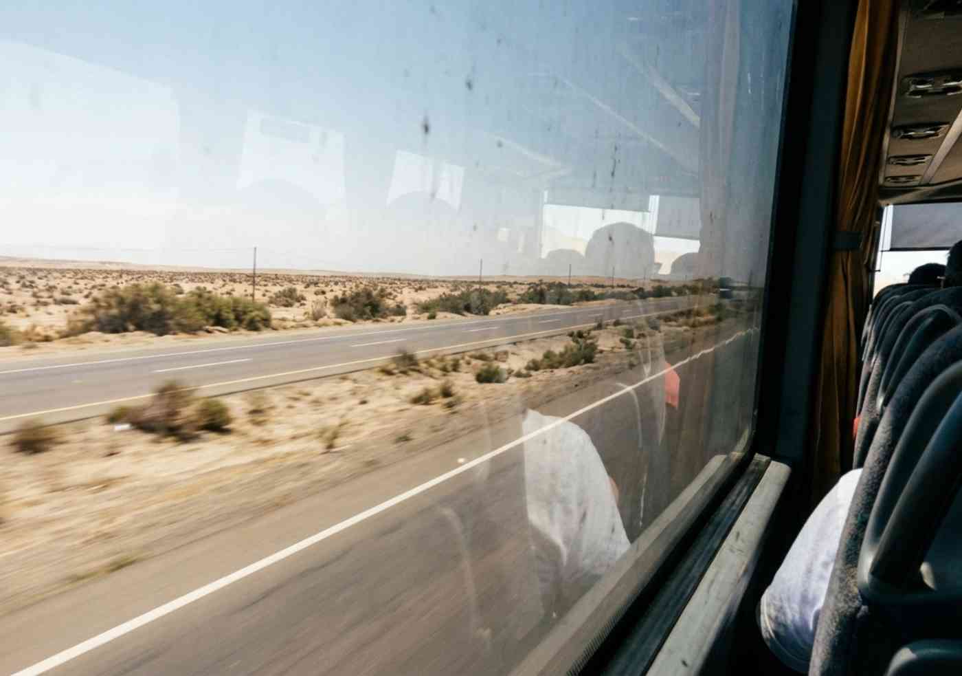 Interior de un bus turístico de alta gama recorriendo la carretera Panamericana Sur hacia Ica con vista al desierto.