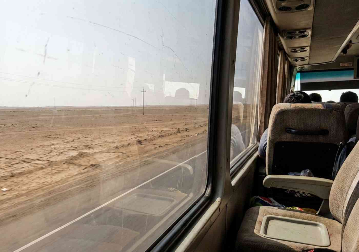 Foto tomada desde la ventana de un bus en movimiento en la carretera Panamericana Sur, mostrando el paisaje desértico camino a Nazca.
