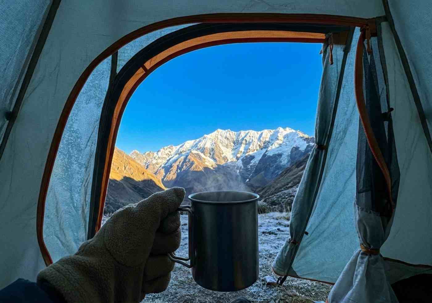 Vista en primera persona desde una carpa en el campamento cerca de Choquequirao, mirando los picos nevados de la cordillera de Vilcabamba bajo un cielo despejado al amanecer.