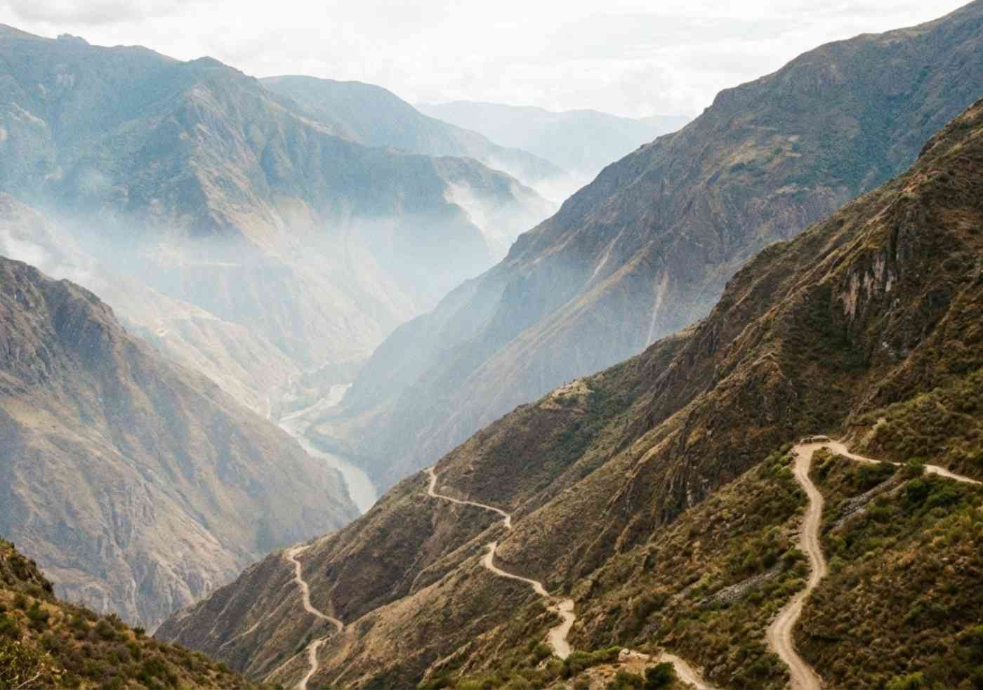 Vista teleobjetivo desde un punto alto mirando hacia el fondo profundo del valle del Apurímac, con el camino zigzagueante visible y una ligera bruma de calor en el aire.